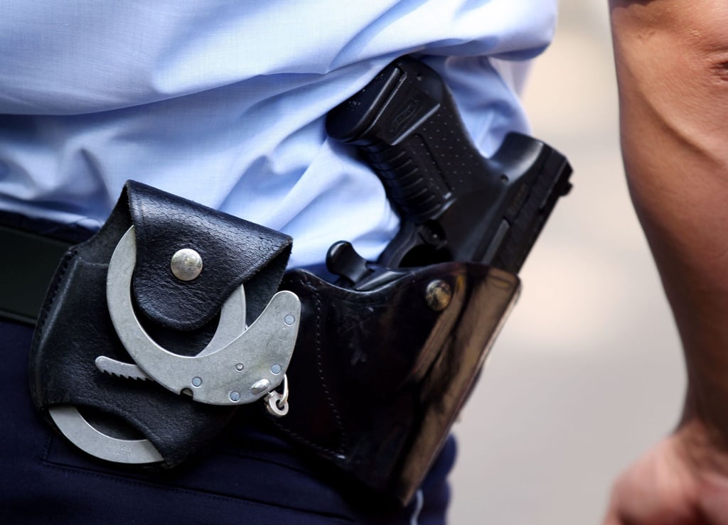 Ein Polizist trägt Handschellen und seine Dienstwaffe bei sich.