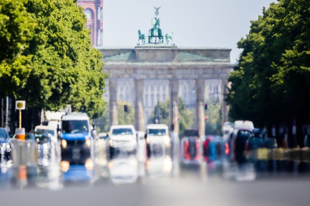 Autos fahren hinter dem Brandenburger Tor über die Straße des 17. Juni.