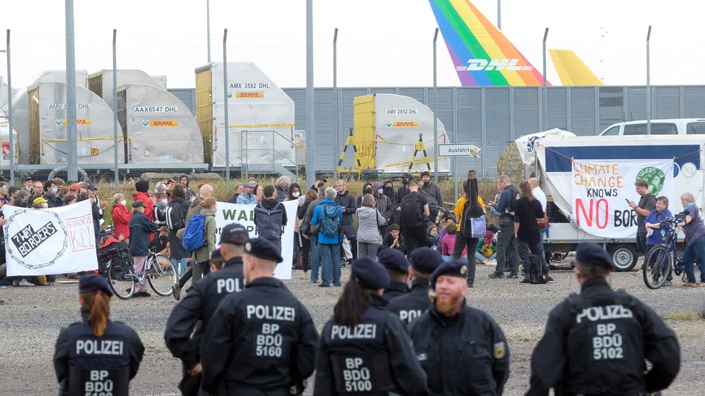 Teilnehmer einer Kundgebung versammeln sich vor dem Zugangstor des Luftfrachtunternehmens DHL am Flughafen Leipzig-Halle. Etwa 250 Umweltaktivisten protestieren gegen den geplanten Ausbau des Frachtdrehkreuzes. Foto: Sebastian Willnow/