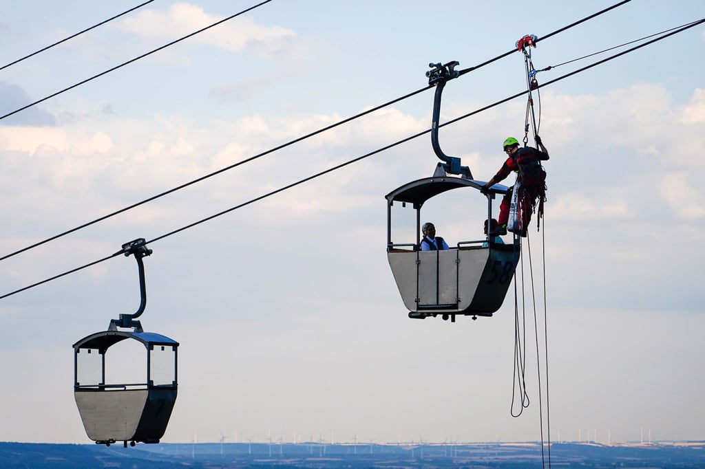 Höhenretter sind an einer stehengebliebenen Seilbahn an einer Gondel mit Passagieren im Einsatz.