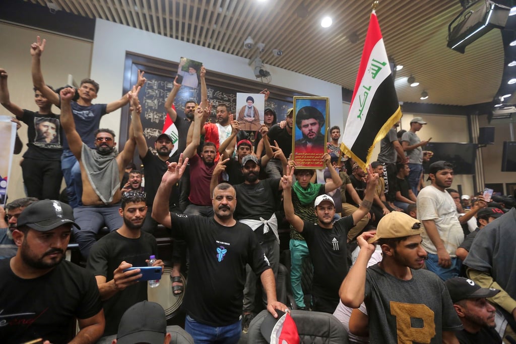 Irakische Demonstranten posieren mit Nationalflaggen und Bildern des schiitischen Geistlichen Al-Sadr vor dem Parlamentsgebäude.