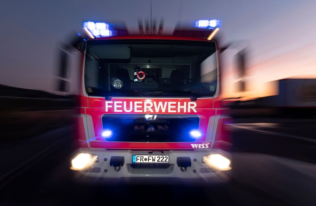 Ein Feuerwehrfahrzeug steht mit eingeschaltetem Blaulicht auf einer Straße.