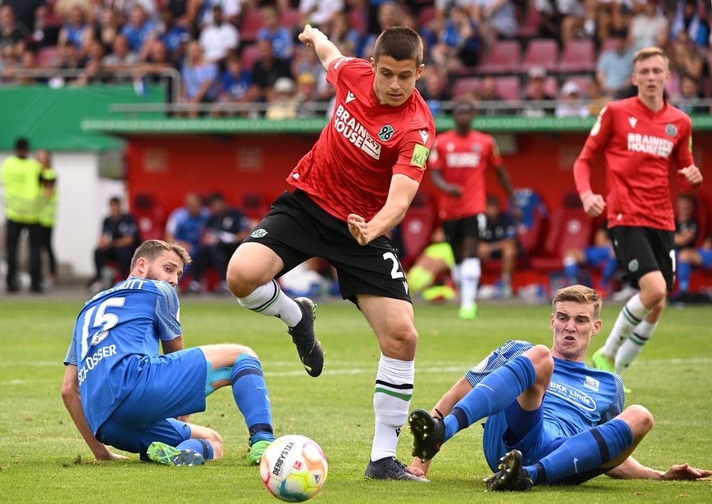 Hannovers Nicolo Tresoldi (M) spielt gegen den Mainzer Nicklas Schlosser (l) und den Mainzer Dominik Ahlbach.