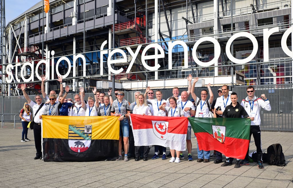 Einige Mitglieder des Teams Sachsen-Anhalt aus Polizisten, Feuerwehrleuten, Zöllnern und Justizbediensteten stehen vor der Eröffnung der Wettbewerbe der „World Police and Fire Games“ im Feyenord-Stadion in Rotterdam für ein Mannschaftsfoto zusammen. Mit dabei auch Magdeburger.