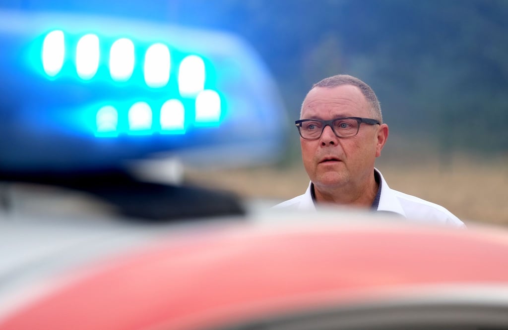 Michael Stübgen steht neben einem Feuerwehrfahrzeug in der Waldbrandregion Elbe-Elster.