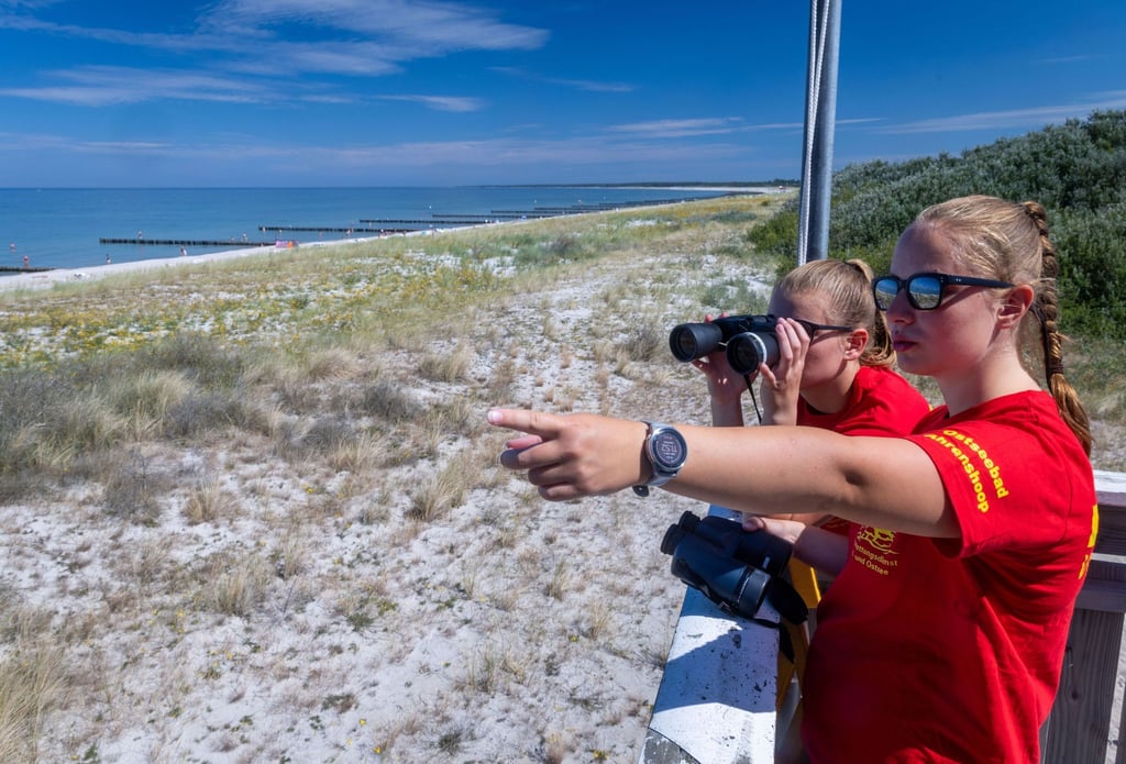 Die Rettungsschwimmerinnen Linda (hinten) und Charlotte beobachten vom Hauptturm der DLRG am Ostseestrand auf der Halbinsel Darss-Fischland-Zingst den Badebetrieb.