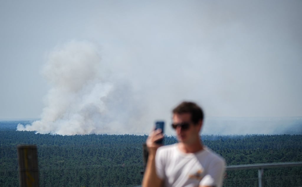 Rauch steigt hinter einem Touristen auf dem Teufelsberg bei einem Brand im Grunewald auf.
