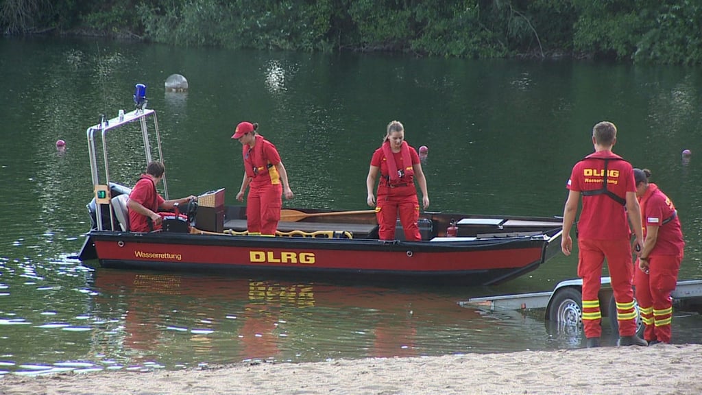 Mitarbeiterinnen und Mitarbeiter der DLRG suchen auf einem Badesee nach einem Jugendlichen in Nordrhein-Westfalen.