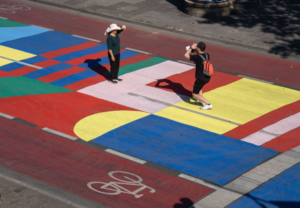 Touristen nutzen die bunt bemalte Fahrbahn am Mainkai für ein Erinnerungsfoto.