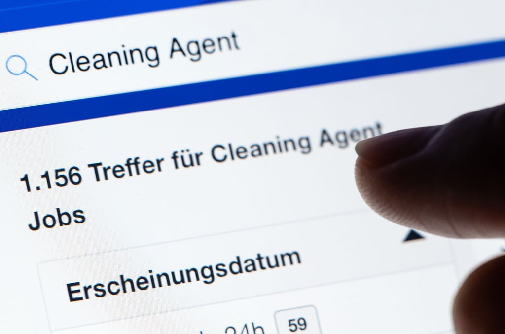 Eine Frau sucht unter der Jobbezeichnung "Cleaning Agent" auf einem Stellenportal auf ihrem Tablet nach Stellenanzeigen.