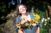 Claudia Werner steht mit einem Eimer mit frisch geschnittenen Blumen in ihrem Garten. Früher arbeitete die Bremerin als Erzieherin - heute hat sie eine eigene Gärtnerei.