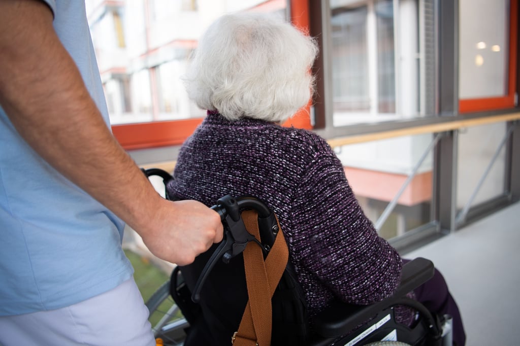 Ein Pfleger schiebt eine Bewohnerin durch ein Pflegeheim: Rund 9000 Beschäftigte im Pflegewesen in Sachsen-Anhalt haben bislang noch keinen Corona-Impfnachweis vorgelegt.