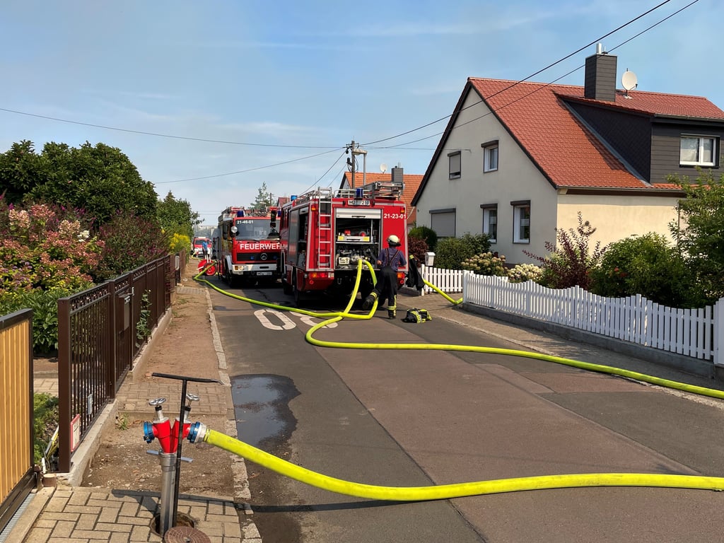 Die Feuerwehr zapft einen Hydranten in der Siedlung an, um das Feuer löschen zu können.