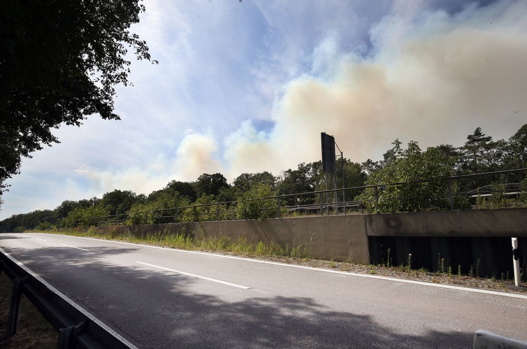 Dunkle Rauchsäulen steigen über der Avus an der Abfahrt Hüttenweg in den Himmel.