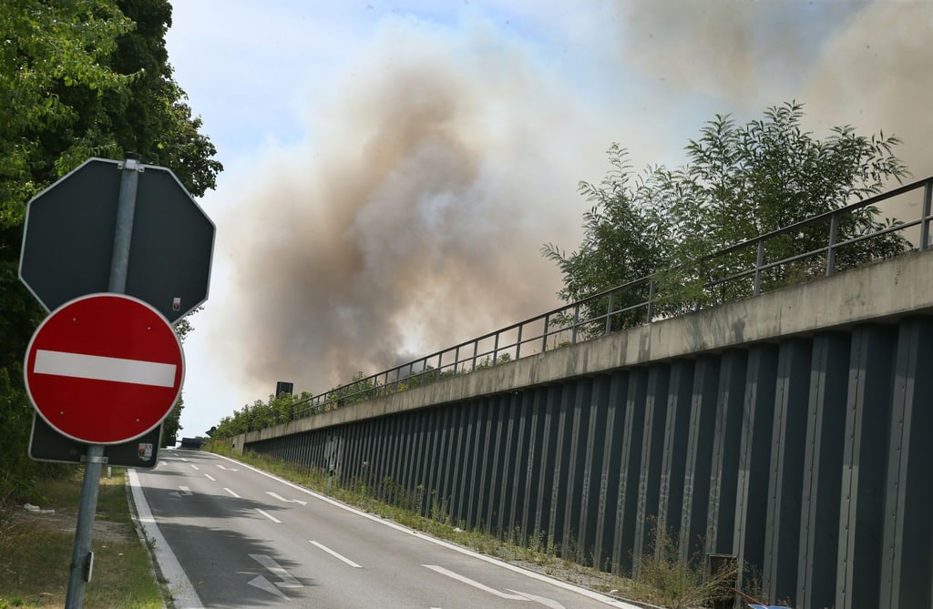 Eine dunkle Rauchsäule steigt über der Avus an der Abfahrt Hüttenweg in den Himmel.