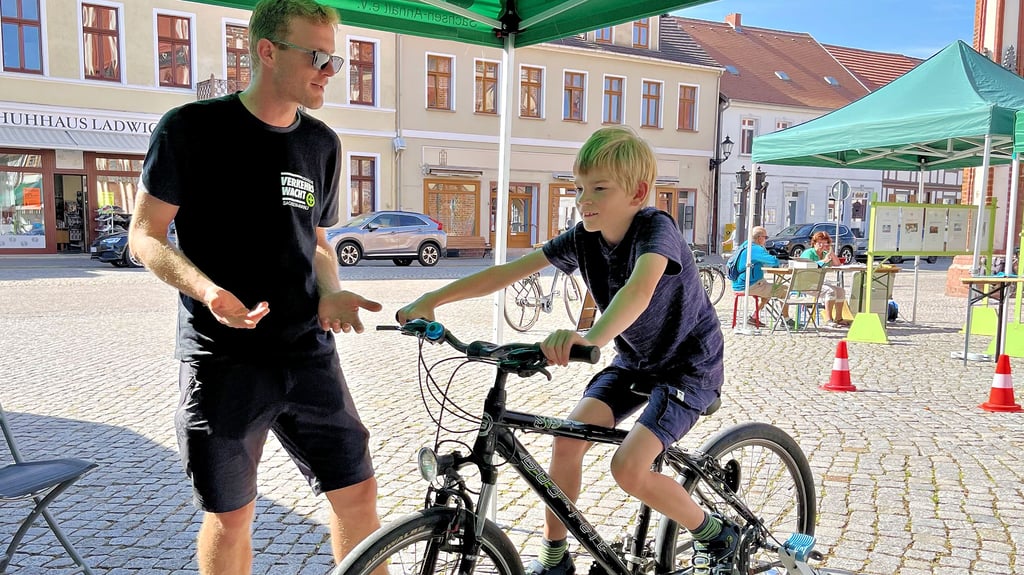 Thorben Prox (9) aus Tangermünde hat sich auf den Tag mit der Verkehrswacht auf dem Tangermünder Marktplatz gefreut. Ronny Buck von der Landesverkehrswacht macht ihn auf dem Fahrradsimulator mit Situationen auf der Straße vertraut.