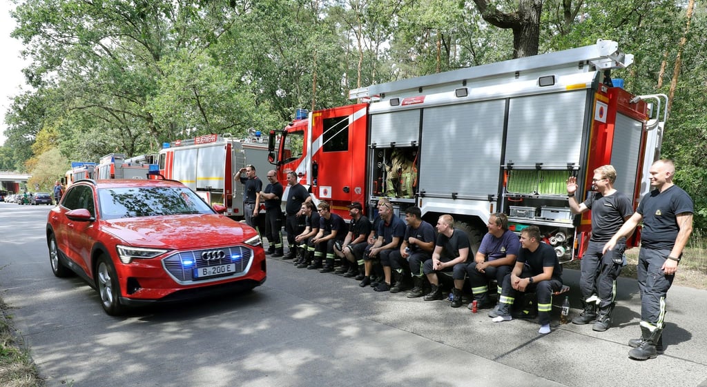 Feuerwehrleute stehen und sitzen an ihren Fahrzeugen und warten auf ihren Einsatz.