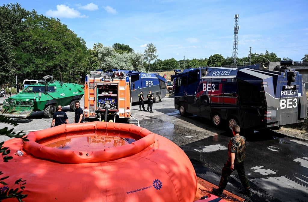 Wasserwerfer, Einsatzfahrzeuge der Feuerwehr und eine Pufferbecken stehen in der Nähe der Brandstelle.