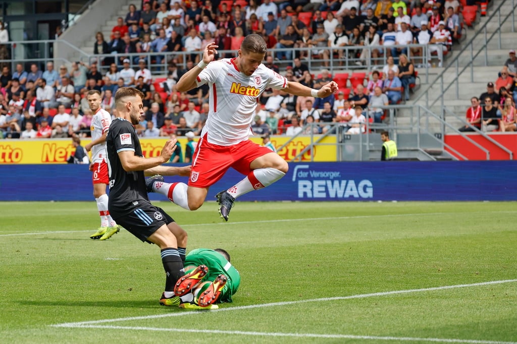 Regensburgs Torhüter Dejan Stojanovic (M) rettet den Ball vor dem Nürnberger Manuel Wintzheimer (l) - Jahn-Spieler Jan Elvedi springt drüber.