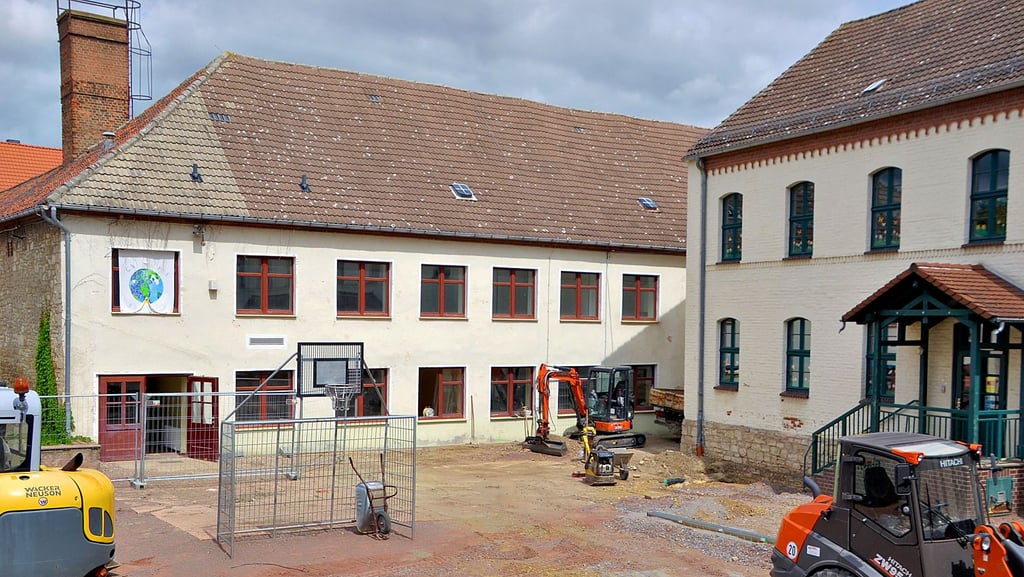 Das hintere Gebäude wird zum neuen Schulhaus umgebaut. In das rechte Gebäude ist die Grundschule Gröningen vor einem Jahr eingezogen. Im Vordergrund befindet sich die Sportspielfläche.
