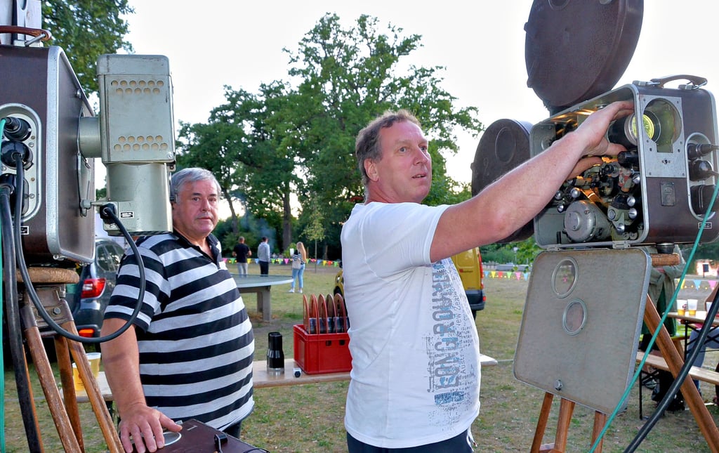 Eyko Pohland richtet einen der beiden Filmprojektoren auf die Leinwand aus. Filmvorführer Uwe Höppner stand ihm beratend zur Seite. Rechts in dem Kasten  am Projektor befindet sich die Lichtwurflampe.