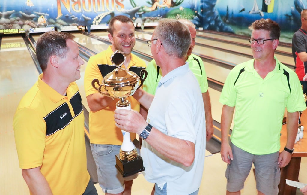 Die Mannschaft vom Schul- und Heimatfestverein hat erstmalig das Heimatfest-Bowlingturnier gewonnen. Benno Loff überreicht die Trophäe an die vier Männer.