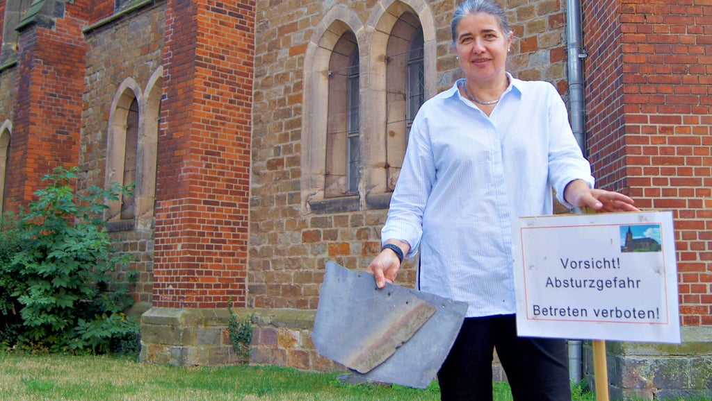 Pfarrerin Ute Kopp zeigt: Zwei Schieferziegel sind schon vom Dach der Katharinenkirche gerutscht. Deshalb ist der Bereich an der Kirche abgesperrt. Die Innenräume der Kirche können gefahrlos genutzt werden, auch der Eingangsbereich ist frei. Dennoch drängt die Zeit, endlich das Dach des Kirchenschiffes zu sanieren.