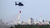 Ein Hubschrauber der Bundespolizei wirft Wasser über der Brandstelle im Grunewald ab.
