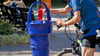 Ein Radfahrer füllt  an einem Trinkbrunnen seine Wasserflasche auf.     