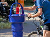Ein Radfahrer füllt  an einem Trinkbrunnen seine Wasserflasche auf.     