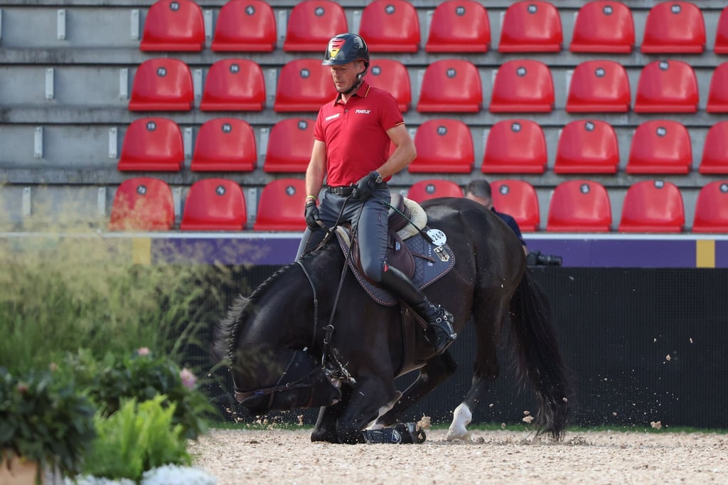 Springreiter Christian Ahlmann bleibt auf Dominator im Sattel während das Pferd beim Training niederkniet.