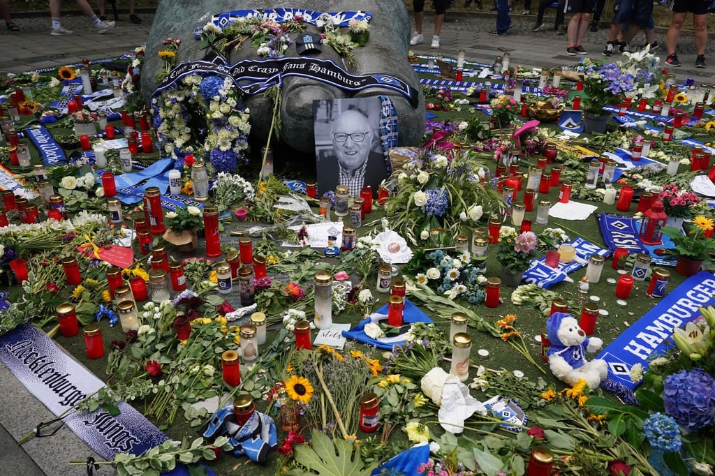Ein Foto von Uwe Seeler und Blumen, Fan-Schals und Trauerlichter stehen an der Bronzeplastik vor dem Volksparkstadion.