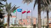 Flaggen in den Farben Katars und eine Fifa-Flagge wehen unter Palmen.