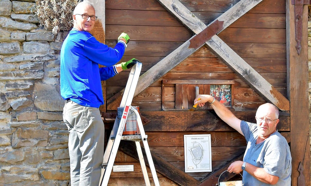Ralf Klaus und Jörg Kunau bringen eine neue Holzlasur an das Braunschweiger Tor an.