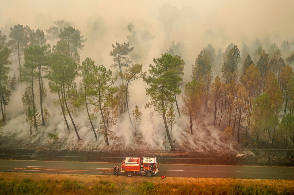 Feuerwehrleute auf einer Straße neben den schwelenden Überresten eines Brandes in der Nähe von Saint-Magne.