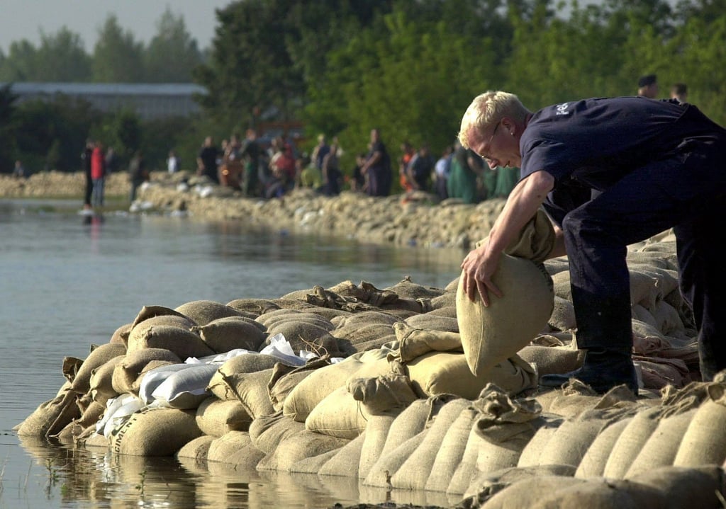 Feuerwehr und freiwillige Helfer schichten am Freitag (16.08.2002) Sandsäcke an das Ufer der Goitzsche in Bitterfeld.