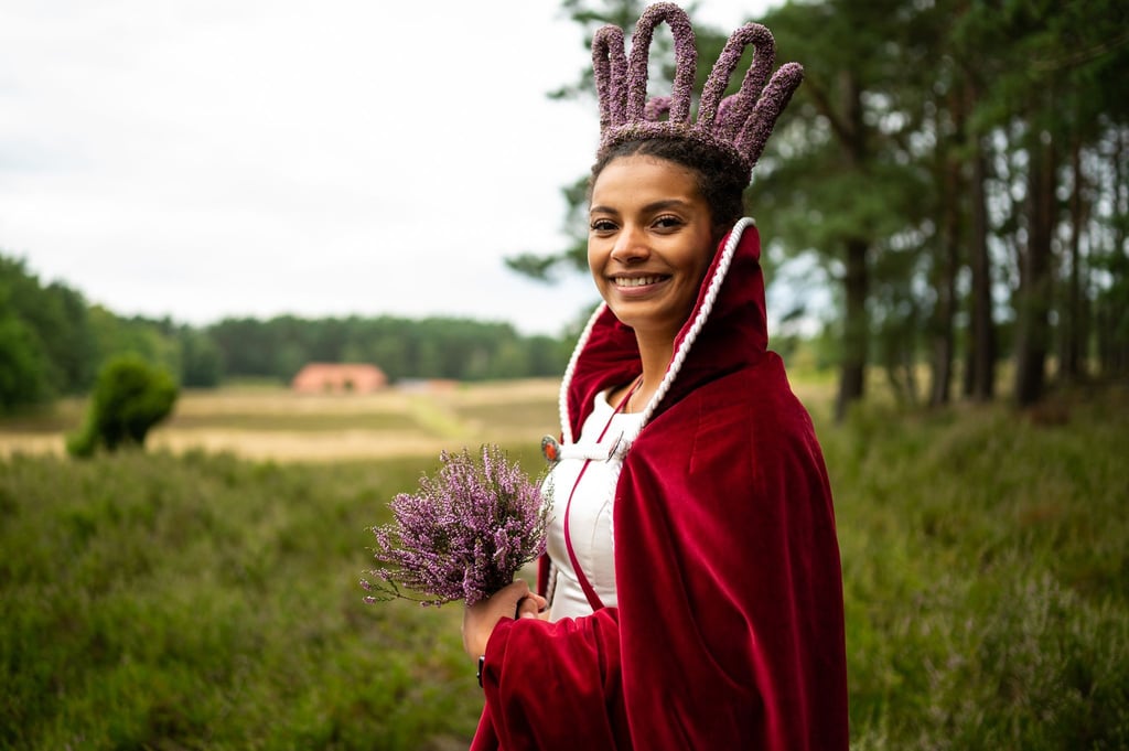 Leonie Laryea, Heideblütenkönigin, steht in der Heidelandschaft.
