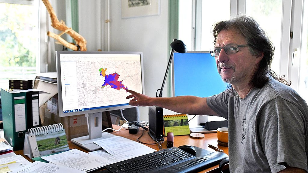 Fred Braumann zeigt auf die Karte des Biosphärenreservates. Die blauen Flächen sind die Moore.