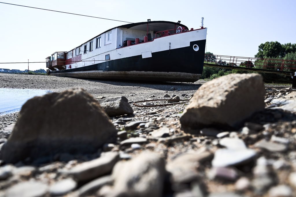 Trockengefallen liegt ein Schiff zwischen den Buhnen am Rhein bei Düsseldorf.