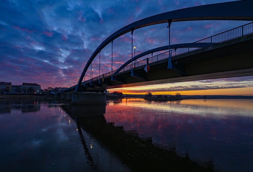 Die aufgehende Sonne strahlt unter der Stadtbrücke am deutsch-polnischen Grenzfluss Oder.