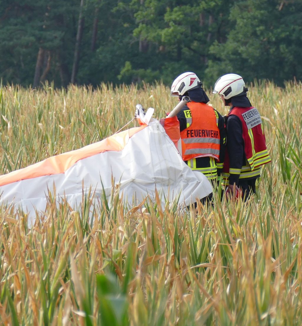 Zwei Feuerwehrleute an der Absturzstelle auf einem Feld bei Niedergörsdorf