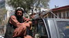 Ein Taliban-Kämpfer sitzt in Kabul mit einem Maschinengewehr auf der Ladefläche eines Fahrzeugs.