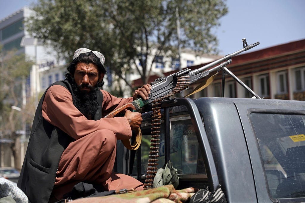 Ein Taliban-Kämpfer sitzt in Kabul mit einem Maschinengewehr auf der Ladefläche eines Fahrzeugs.