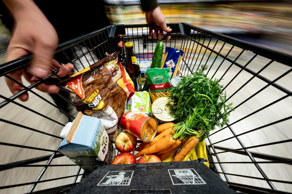 Verschiedene Waren liegen in einem Einkaufswagen in einem Supermarkt.
