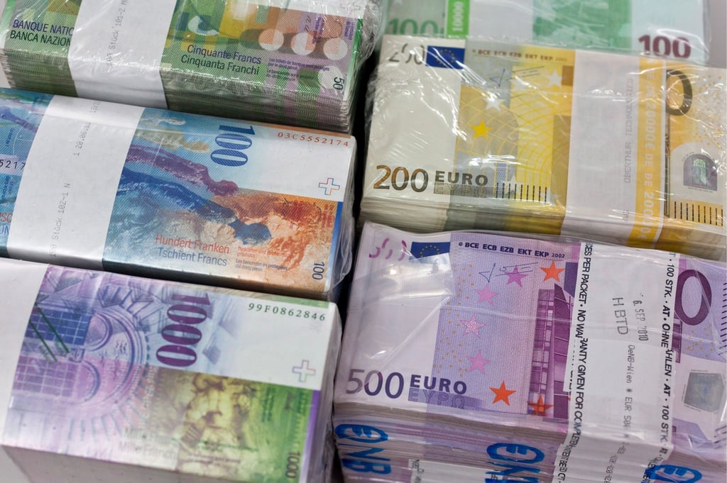 Bündel von Banknoten in Franken und Euro liegen auf einem Tisch.