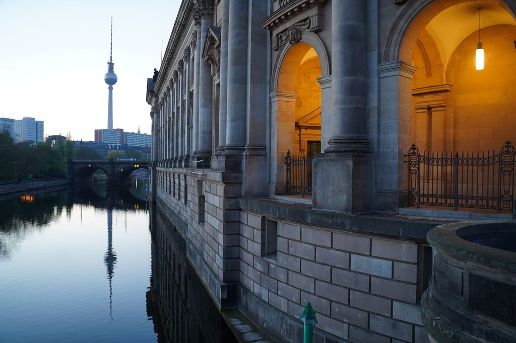 Blick auf das beleuchtete Bode-Museum und den Fernsehturm am frühen Morgen.