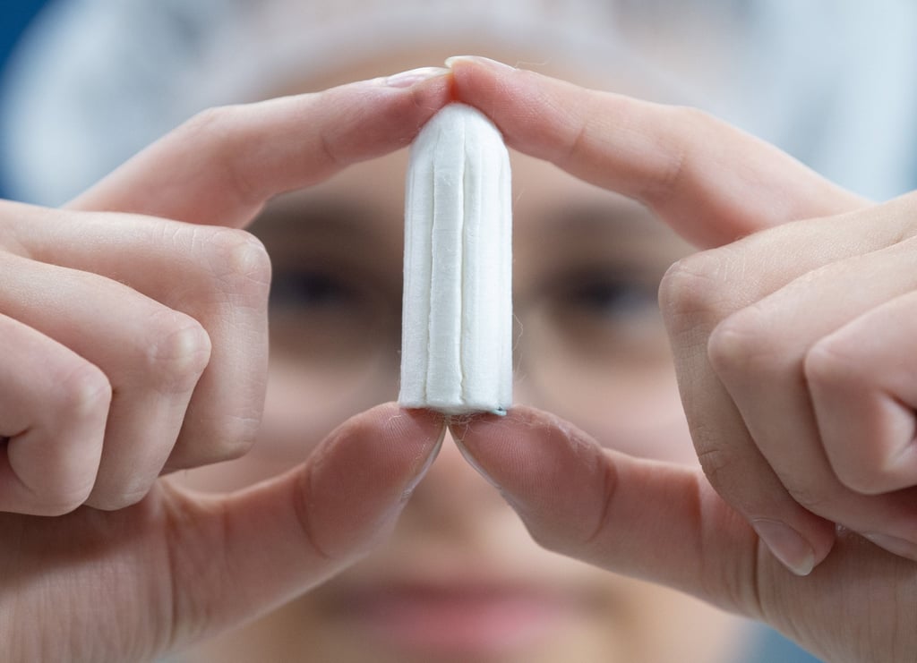 Illustration: Ein Tampon wird von einer Angestellten in einer Produktionshalle gehalten. Binden und Tampons sind in Schottland nun per Gesetz kostenlos erhältlich.
