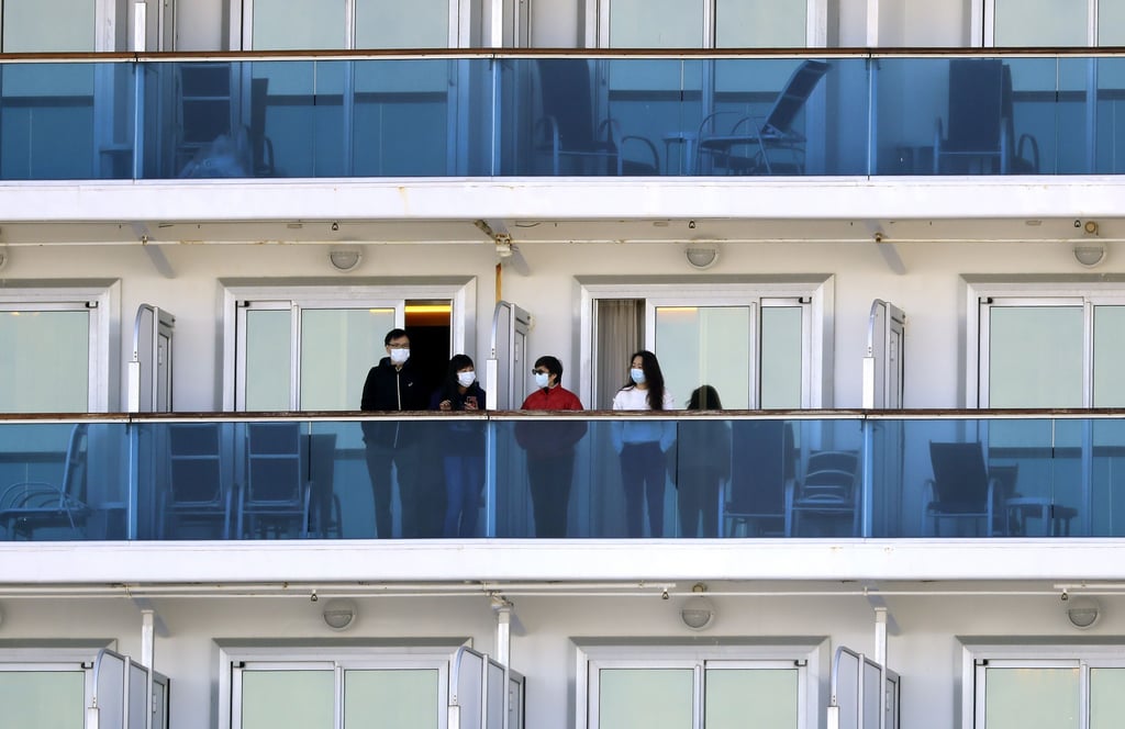 Frust statt Reiselust durch Quarantäne: Urlauber stehen mit Masken auf den Balkonen ihrer Unterkunft.