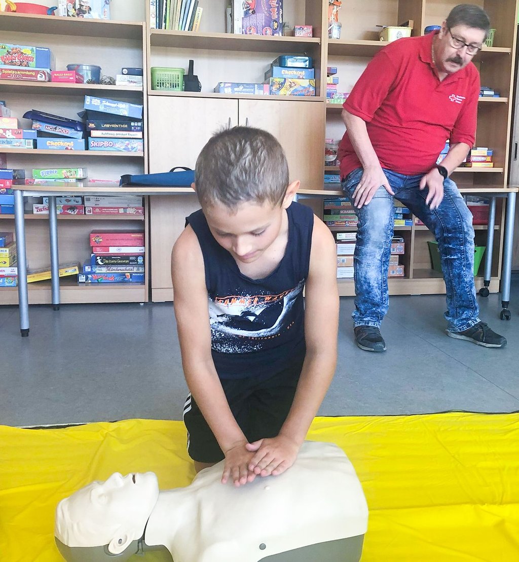 Der achtjährige Emilian führt die Herzdruckmassage an einem Dummy durch. Ralf Glaubel vom DRK schaut ihm dabei über die Schulter.