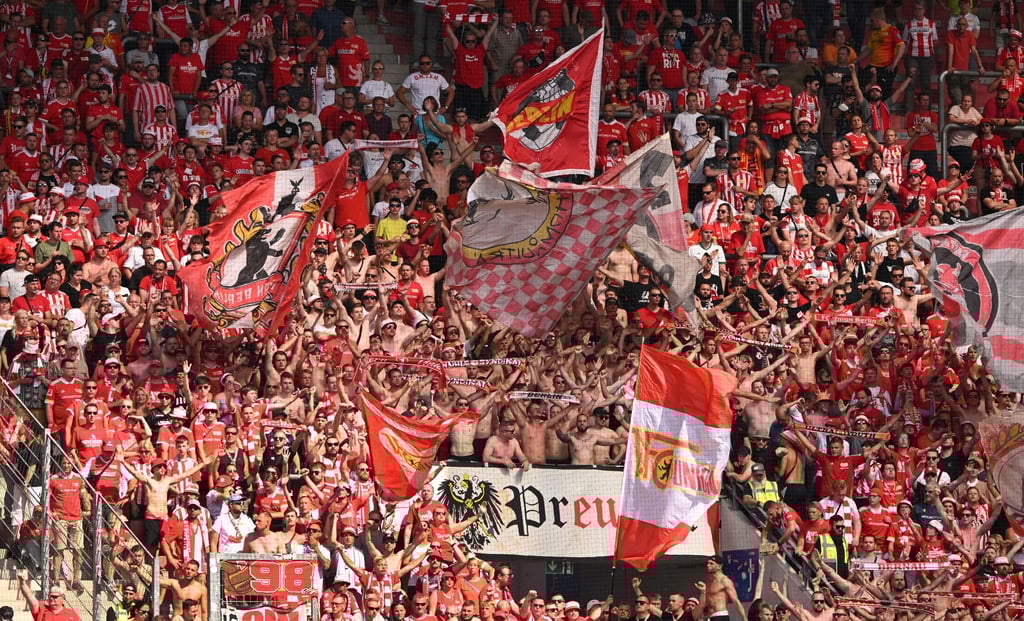 Fans von Union Berlin schwenken beim Spiel gegen Mainz Fahnen.